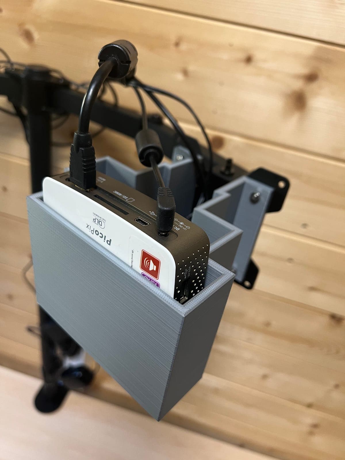 Il proiettore nel contenitore stampato in 3D, con i cavi HDMI e di alimentazione raccolti sul braccio.